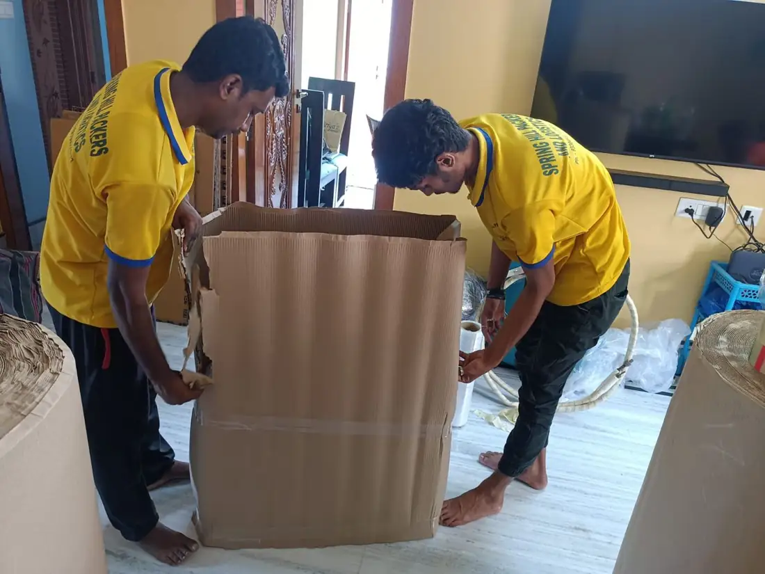 Crew sliding a carton over a tall furniture piece