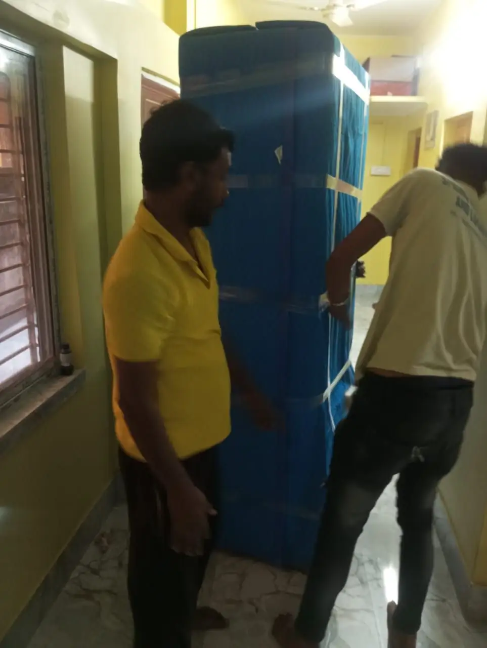 Crew moving a wrapped refrigerator