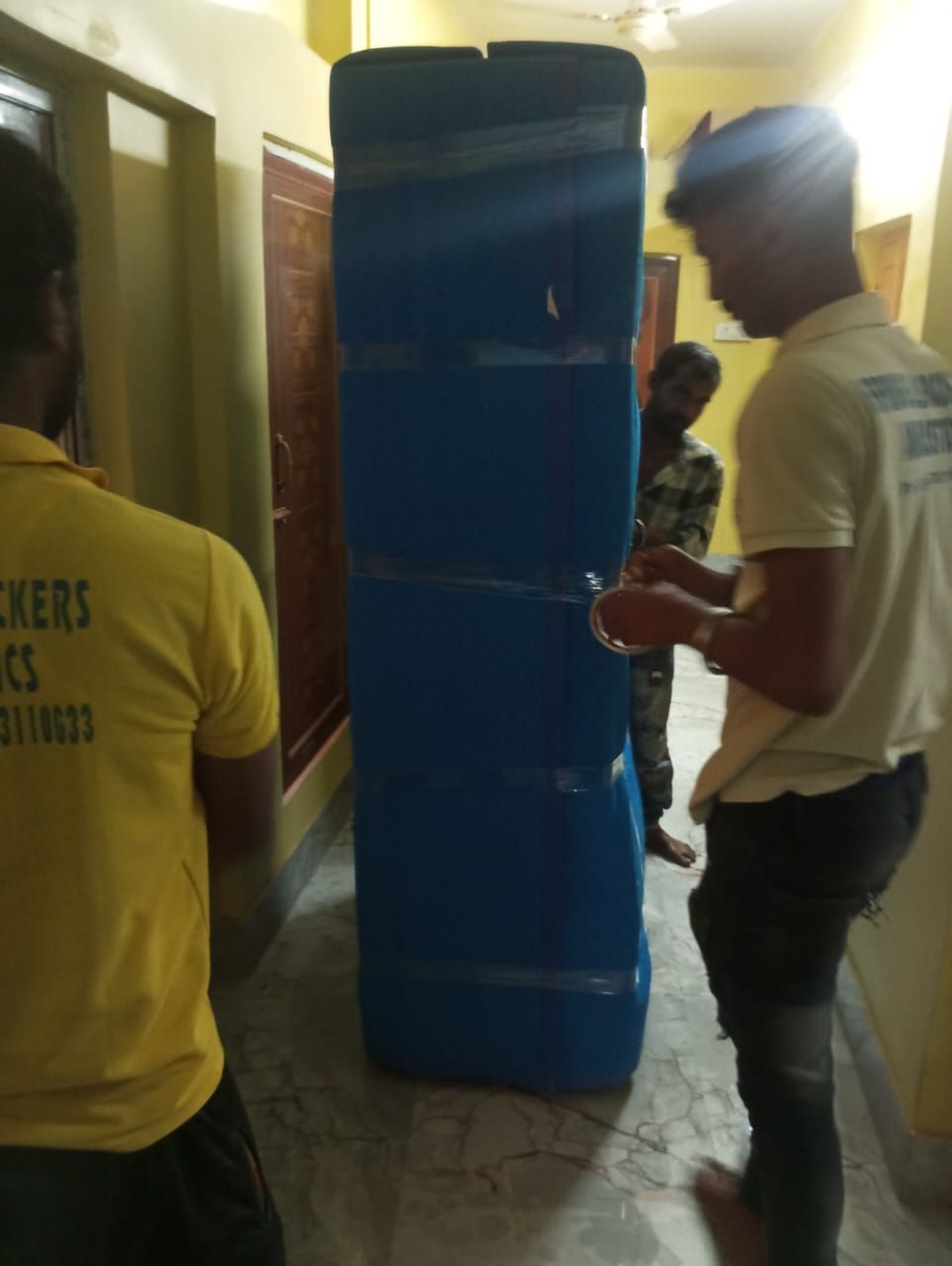 Packer wrapping a refrigerator in blue sheet